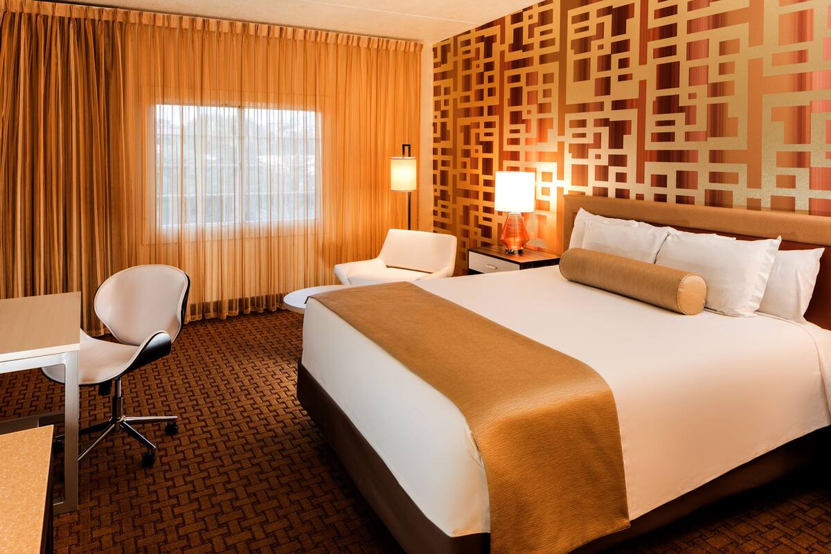 Une chambre d’hôtel avec un grand lit, deux tables de chevet, un bureau et une chaise.