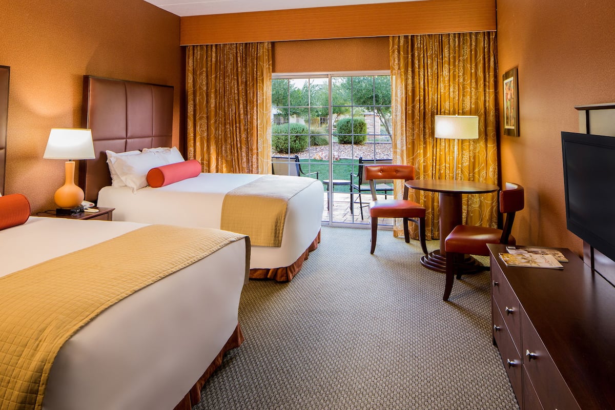 Une chambre d’hôtel avec deux lits, un coin repas et une télévision.