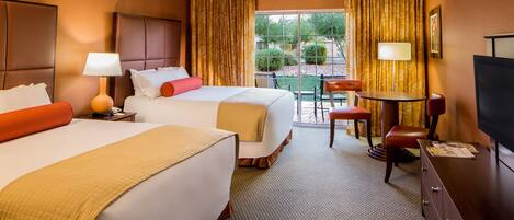 A hotel room with two beds, a dining area, and a TV.