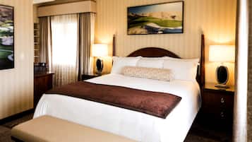 Une chambre d’hôtel avec un grand lit, deux tables de chevet avec des lampes, un banc au pied du lit et un tableau au mur.