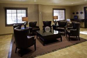 A conference room with a glass table, leather chairs, and a desk with a computer.