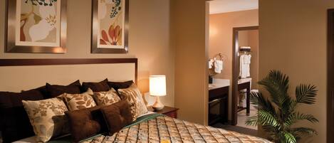 A hotel room with a bed, a tray of breakfast, a lamp, and a plant.