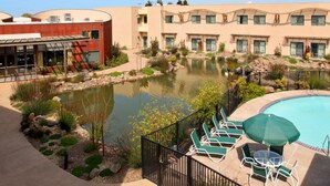 A hotel with a swimming pool, outdoor seating, and a pond. - DoubleTree by Hilton Napa Valley - American Canyon (American Canyon)