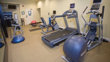Un gimnasio con cintas de correr, elípticas y pelotas de ejercicio.