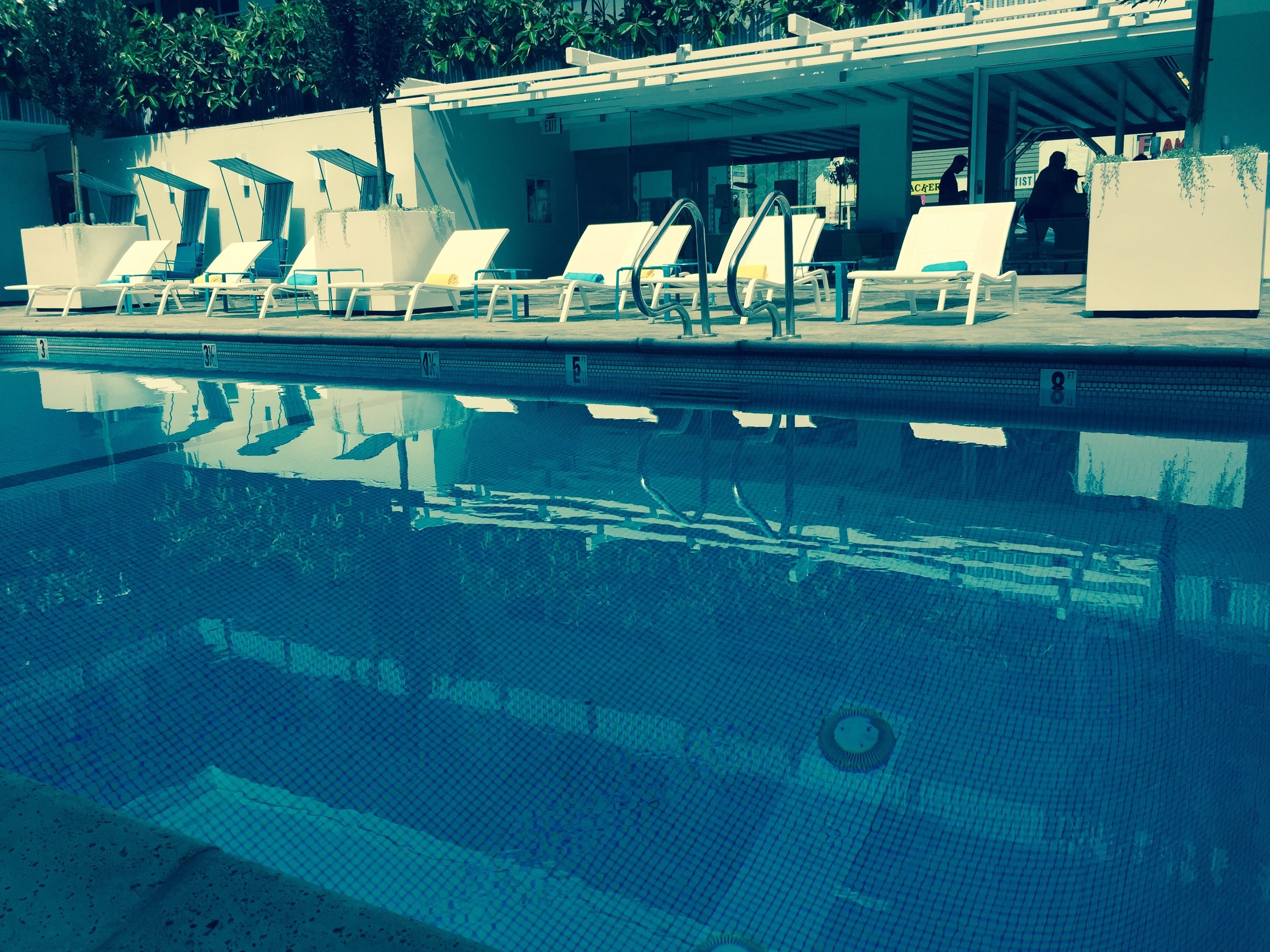 A swimming pool with lounge chairs and a covered area.