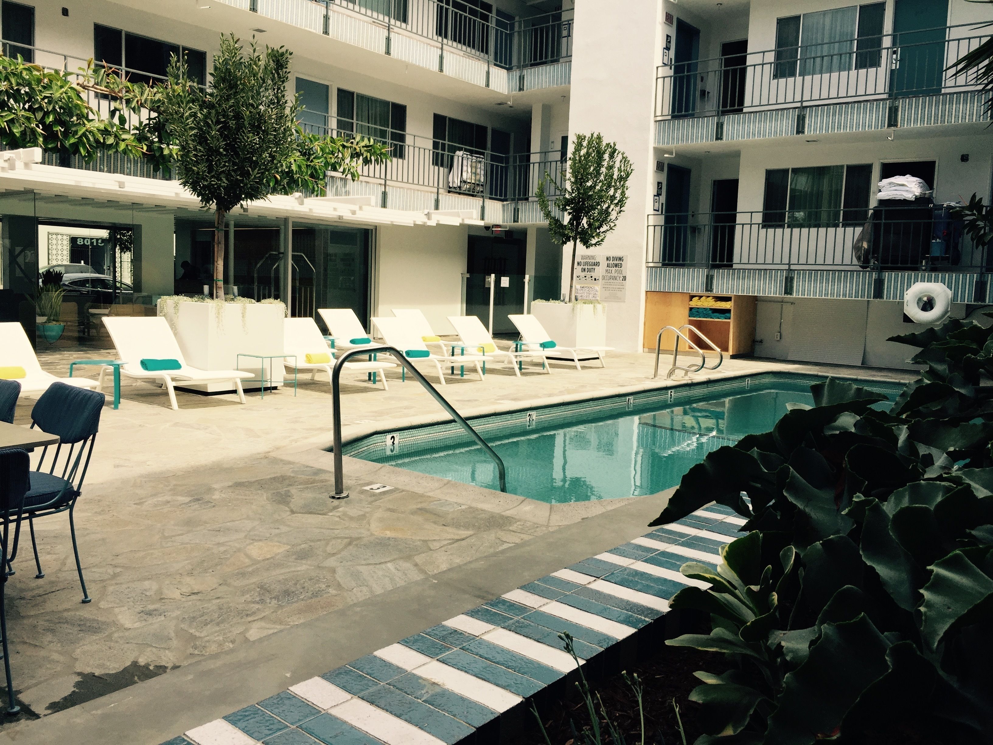 Un espace piscine comprenant des chaises longues, une piscine et un bâtiment doté de plusieurs balcons.