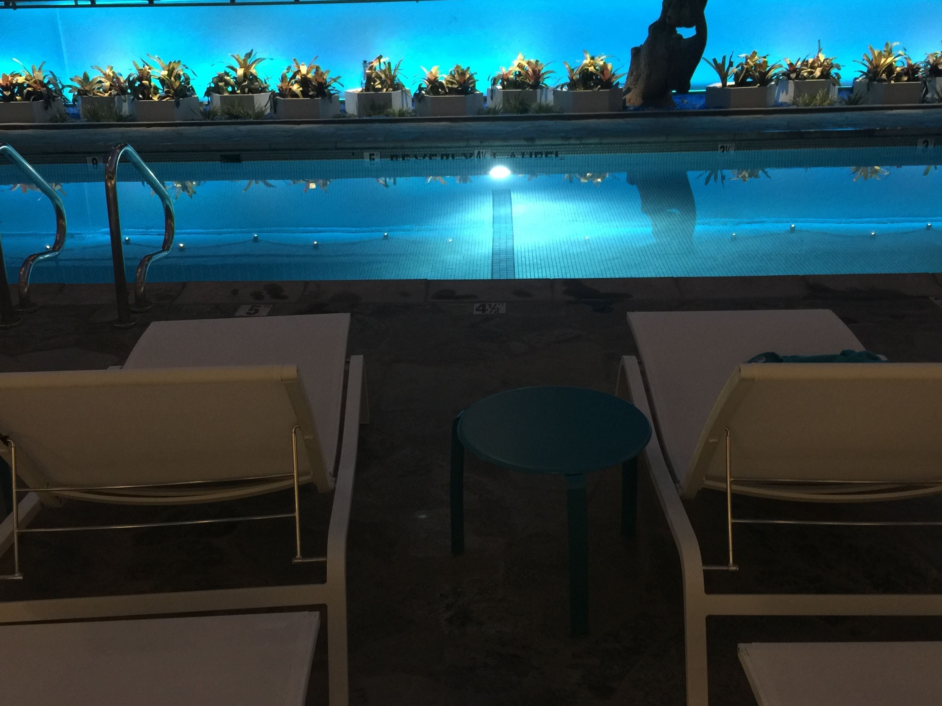 Un espace piscine avec des chaises longues et une petite table.