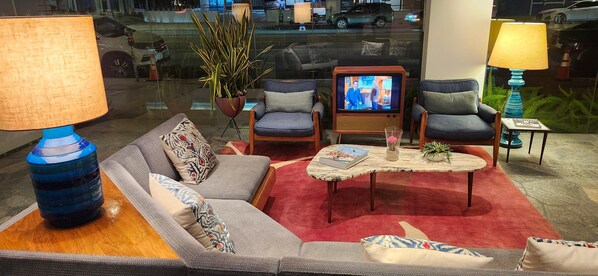 A modern living room with a sofa, two armchairs, a coffee table, and a television.