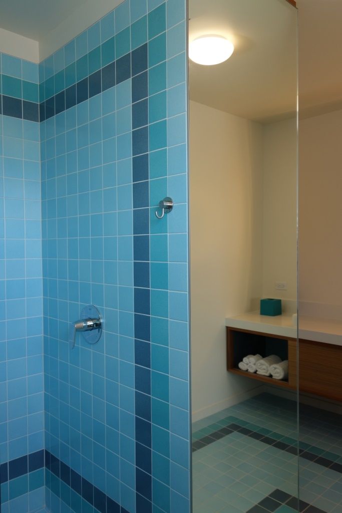 Un baño con paredes de azulejos azules y cabina de ducha de vidrio.