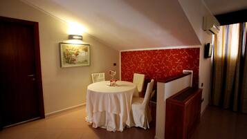 A dining area with a round table, white chairs, a small decorative item, and a wall-mounted light.