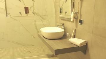 Une salle de bain moderne avec un grand lavabo blanc, un sèche-cheveux et un porte-serviettes.