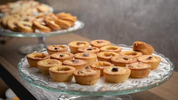 A glass display case with various baked goods, including mini pies and tarts, on a wooden surface.