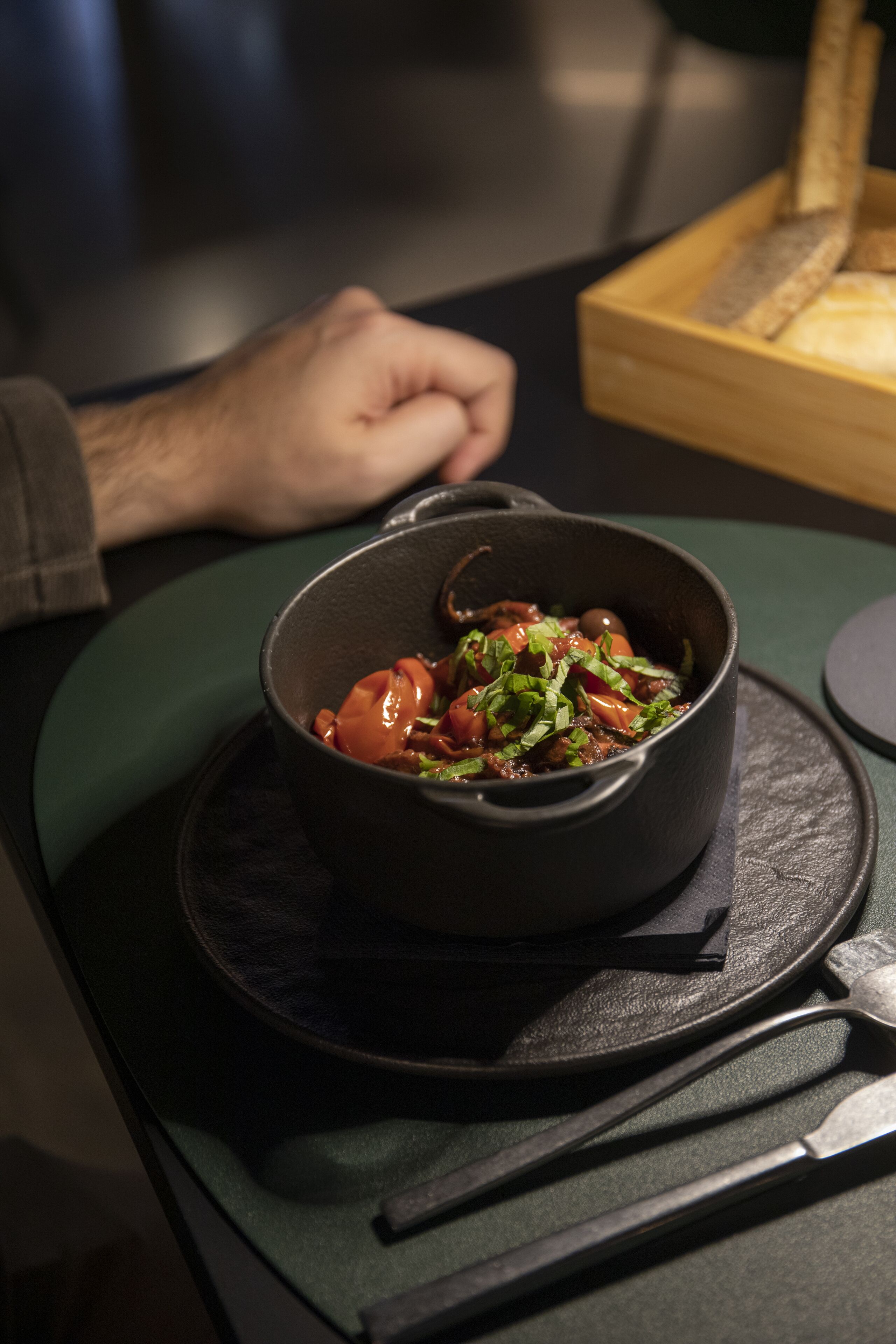Un plato de comida sobre una mesa, con la mano de alguien apoyada en ella.