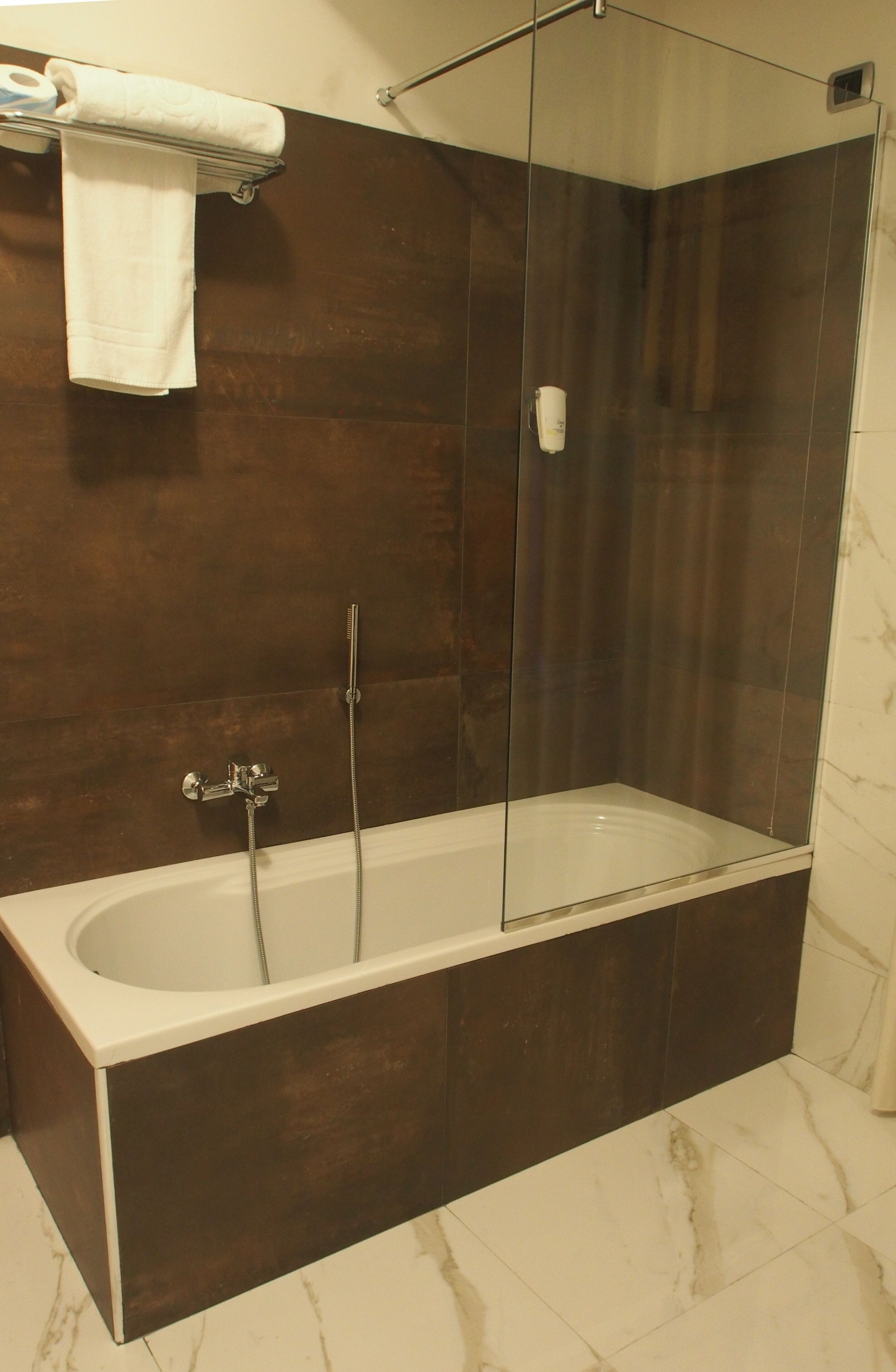 Une salle de bain moderne avec une douche à parois de verre, une baignoire sur pieds et un porte-serviettes.