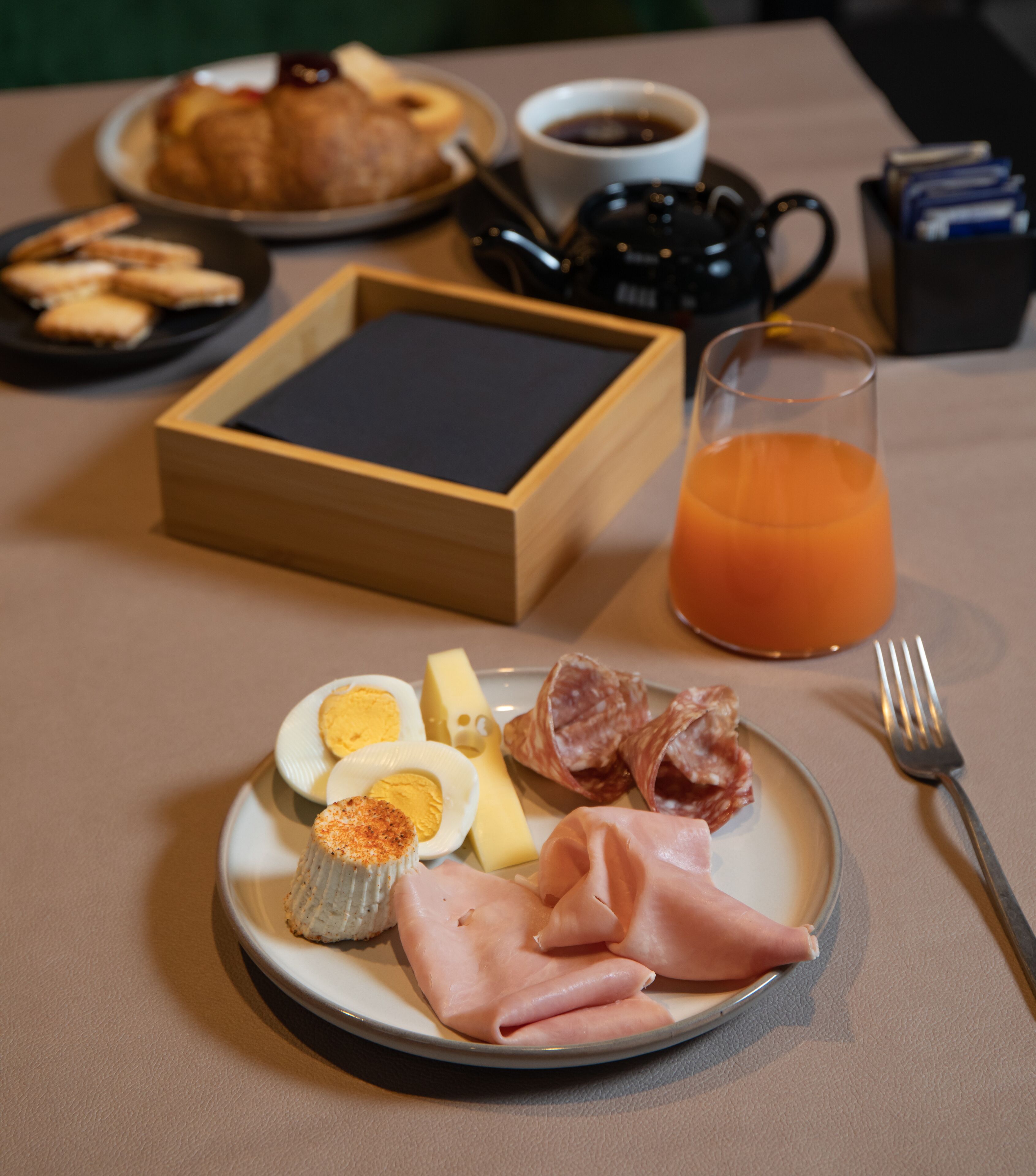 A breakfast plate with eggs, ham, cheese, and a glass of orange juice.