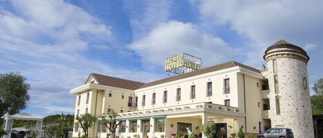 A hotel with a prominent tower and a sign reading "BEL SITO HOTEL".