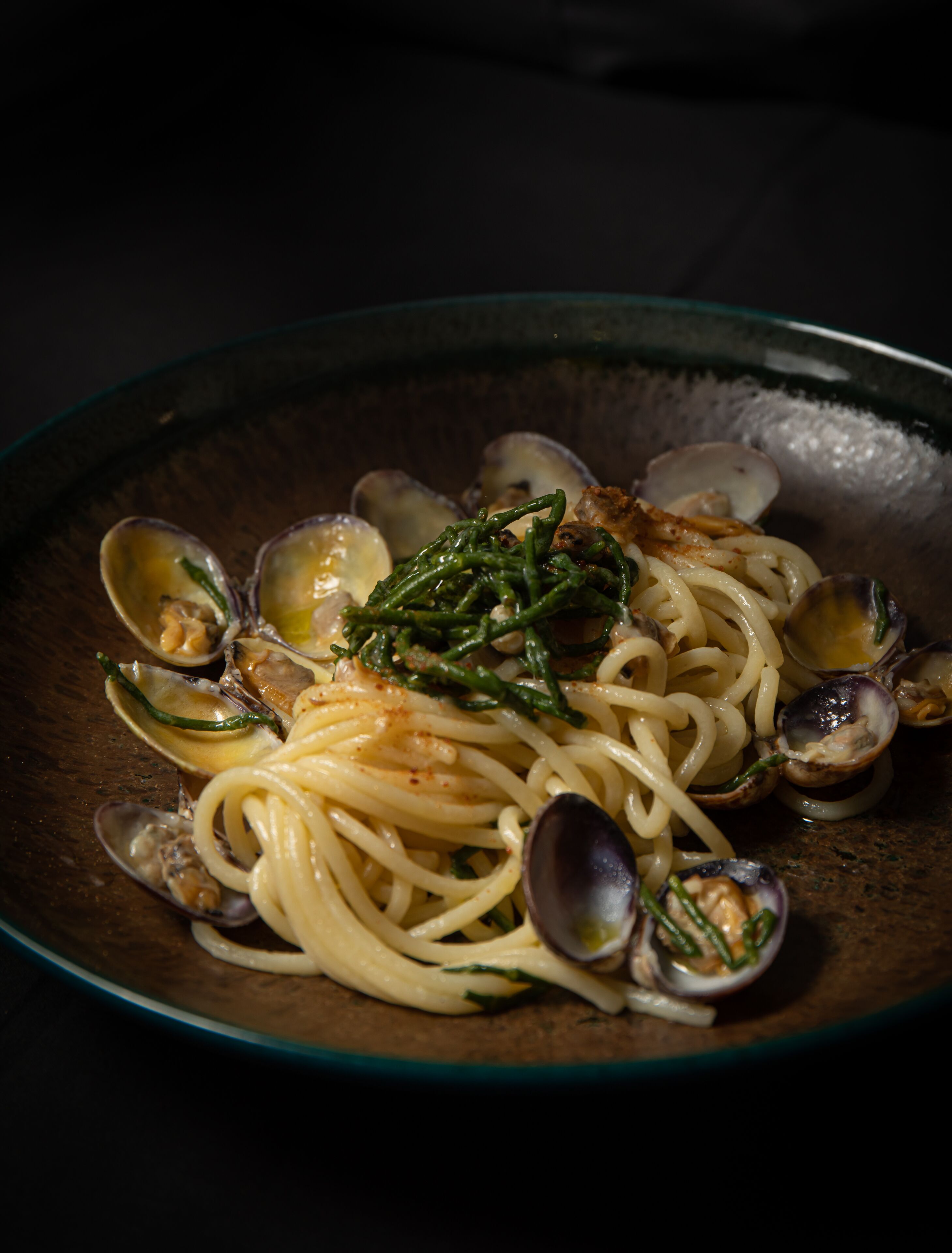 A plate of spaghetti with clams and green beans.