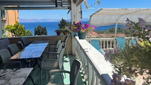 A balcony with a table and chairs, overlooking a pool and the sea. - Andromaches Holiday Apartments (Corfu)