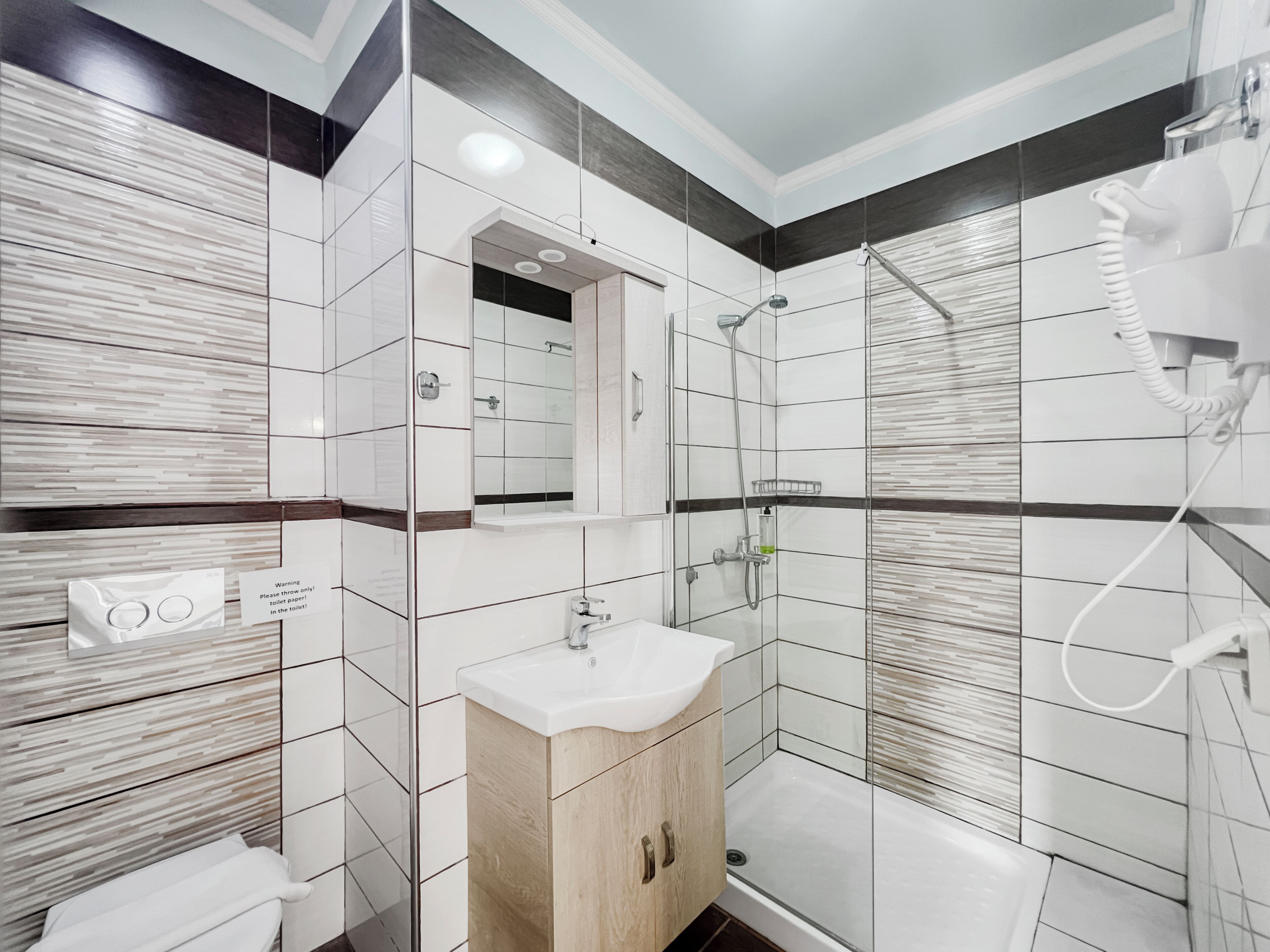 Un baño moderno con cabina de ducha de vidrio, un lavabo con mueble de madera y un perchero para toallas.