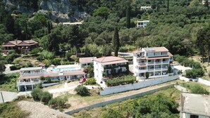 A residential area with multiple two-story houses, a swimming pool, and a paved road. - Andromaches Holiday Apartments (Corfu)