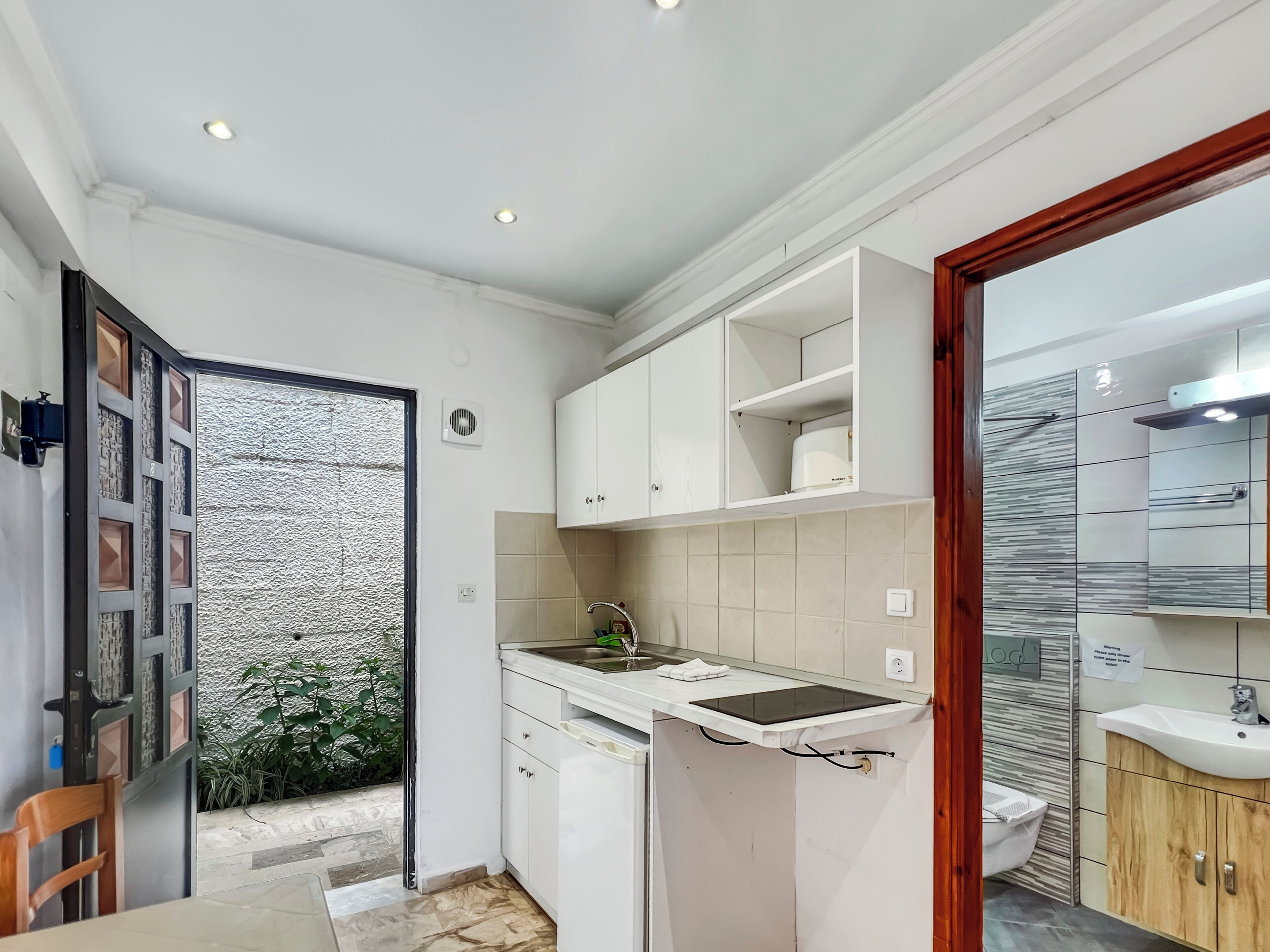 A compact kitchen with white cabinets, a sink, and a small refrigerator.