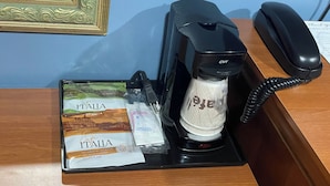 Een koffiezetapparaat, een telefoon en een zak koffie op een bureau.