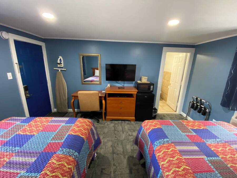 Een hotelkamer met twee bedden, een bureau, een televisie, een magnetron en een kledingkast.