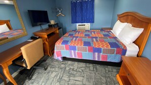 Een hotelkamer met een bed, bureau, stoel, dressoir, spiegel, televisie en een raam met gordijnen.