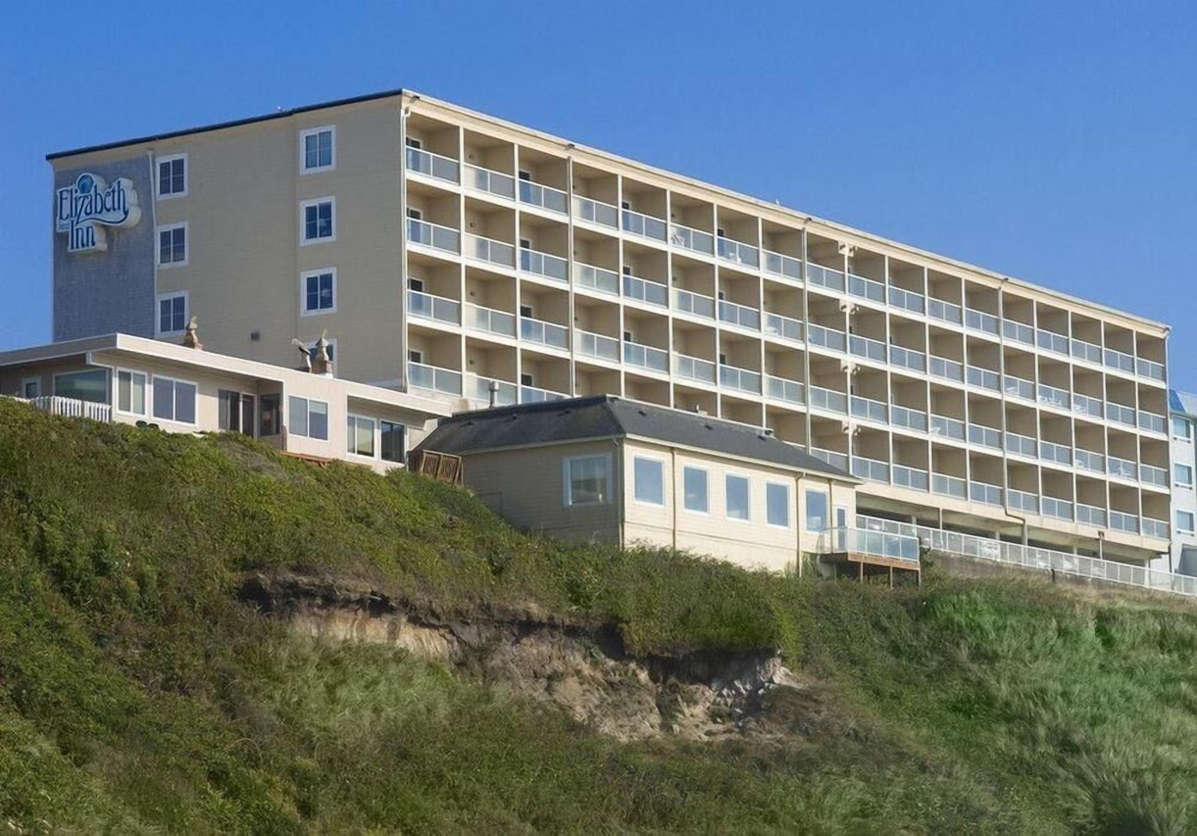 Un hotel de varios pisos con techo plano y un balcón en la planta baja.