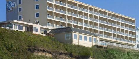 Un hotel de varios pisos con techo plano y un balcón en la planta baja.