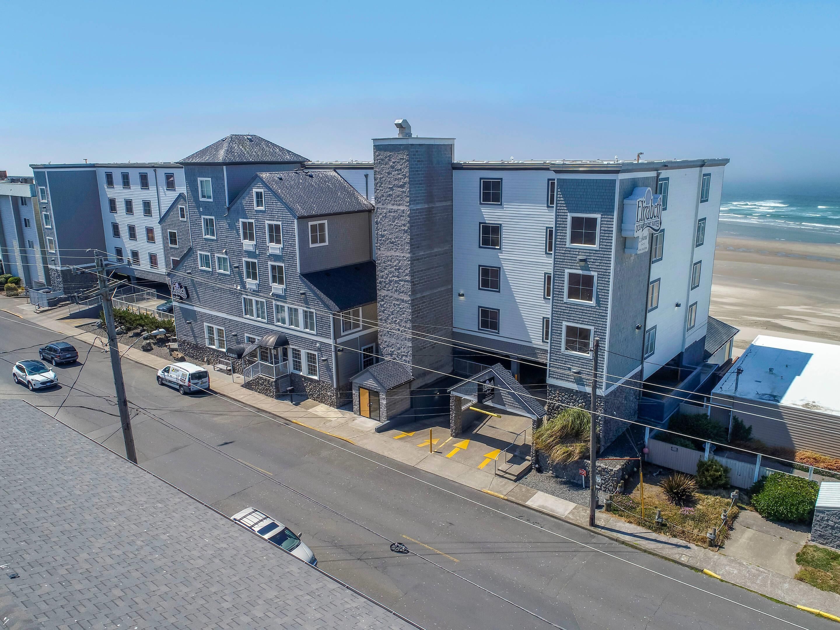 Un hotel de varios pisos con un diseño arquitectónico moderno, que combina materiales de piedra y metal, y una entrada destacada con rampa.