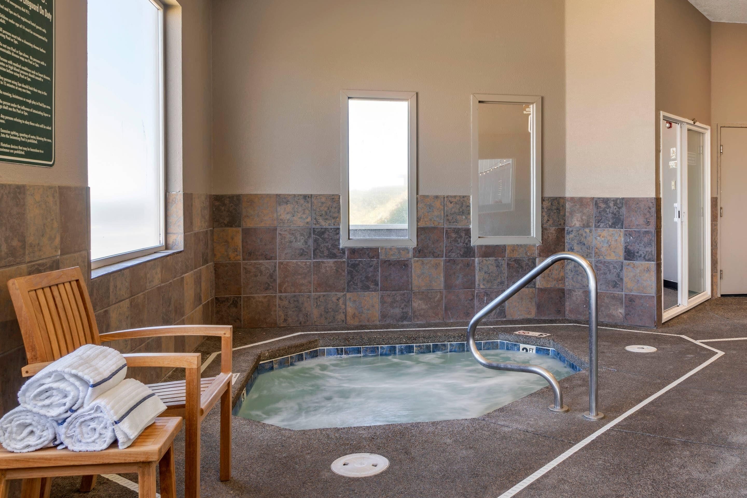 A spa area with a hot tub, wooden chairs, and a tiled wall.