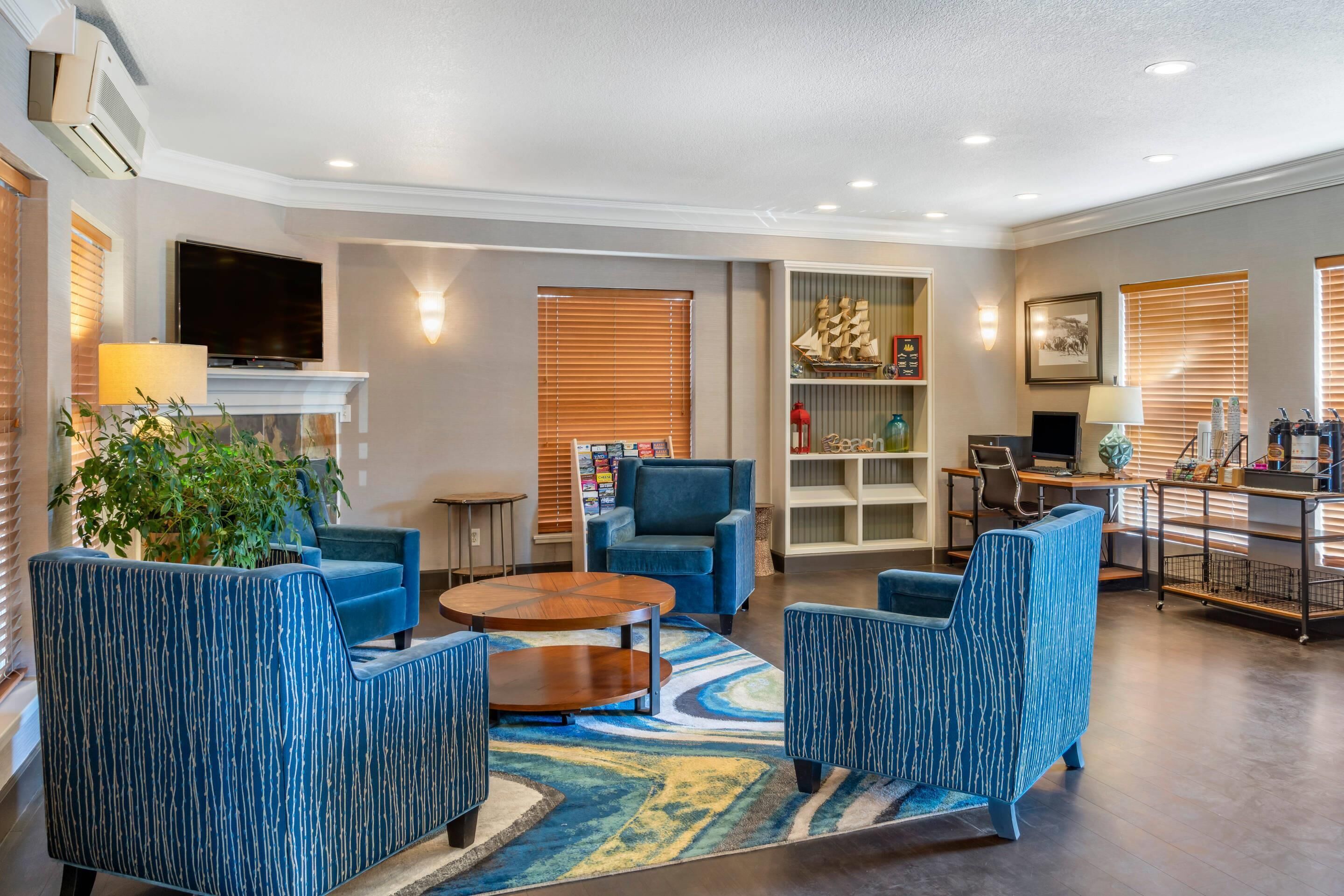Un salon moderne avec des fauteuils bleus, une table basse, un téléviseur à écran plat, une cheminée et une bibliothèque.