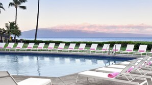 A poolside area with lounge chairs and a view of the ocean. - Kaanapali Ocean Inn (Lahaina)