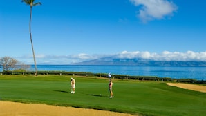 A golf course with a clear view of the ocean and mountains in the background. - Kaanapali Ocean Inn (Lahaina)