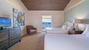 A hotel room with two beds, a television, a chair, and a view of the sea through the window. - Kaanapali Ocean Inn (Lahaina)