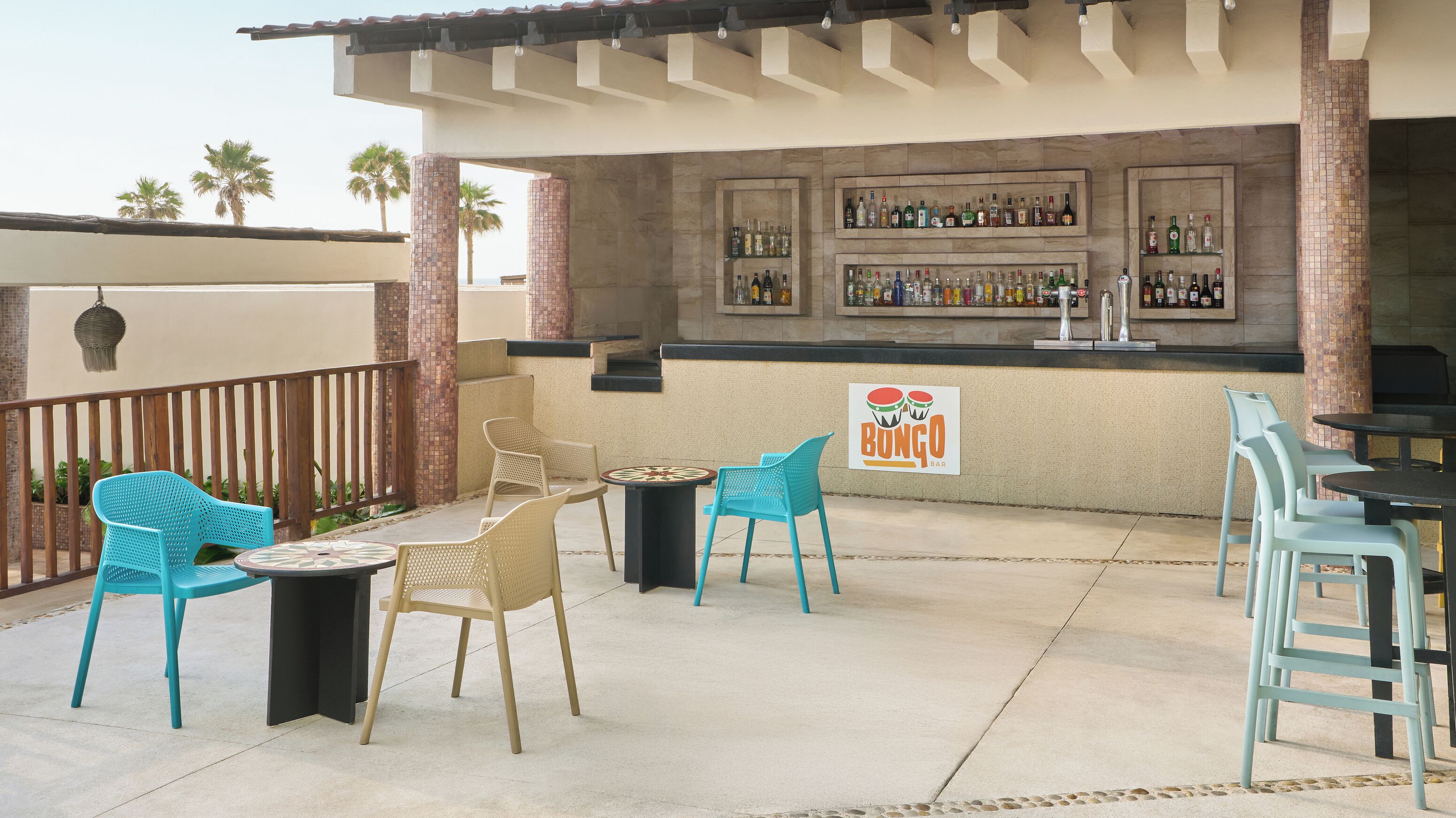 An outdoor bar area with turquoise chairs, a small round table, and a sign for 'Bongo Bar'.