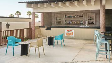 An outdoor bar area with turquoise chairs, a small round table, and a sign for 'Bongo Bar'.