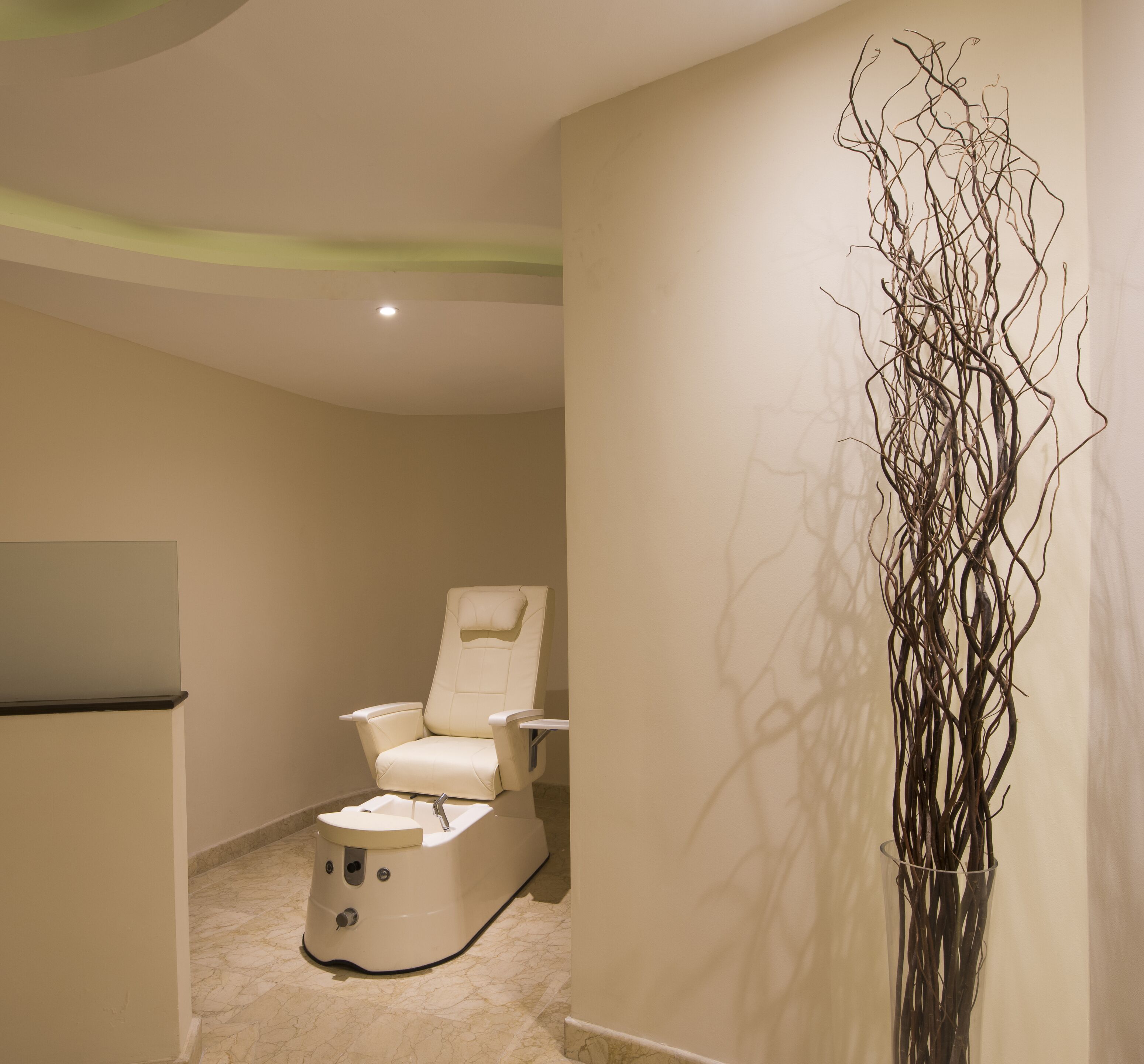 A spa room with a massage chair, a sink, and a decorative branch sculpture.