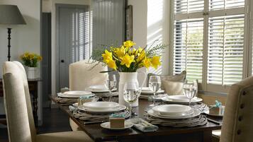 A dining table set with white plates, glasses, and a vase of yellow flowers.