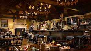 A bar with wooden beams, chandeliers, and a television screen. - Trump International Golf Links And Hotel Doonbeg Ireland (Doonbeg)