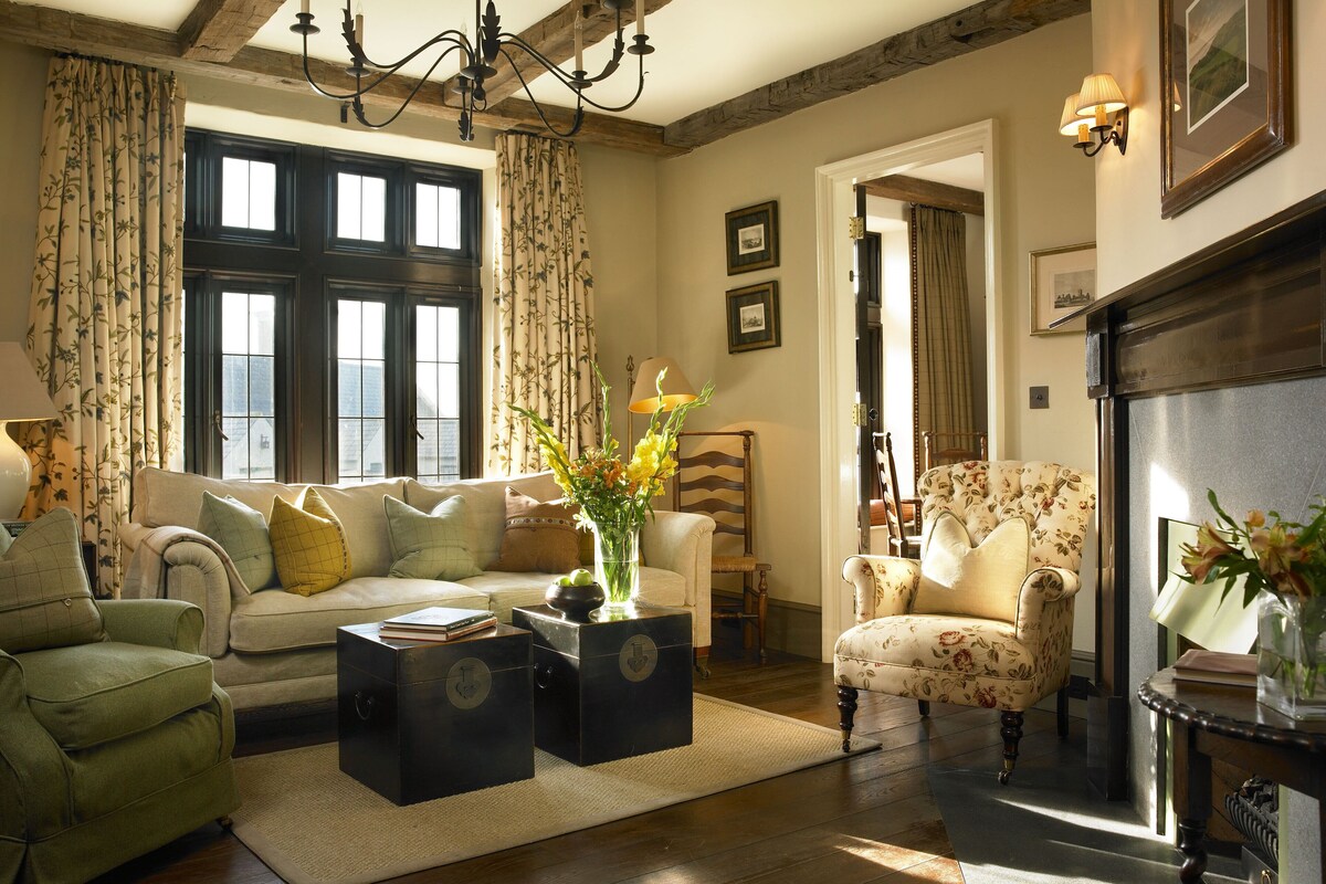 A traditional living room with a fireplace, wooden beams, and classic furnishings.