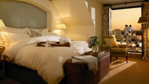 A spacious bedroom with a large bed, a chandelier, and a view of the sea. - Trump International Golf Links And Hotel Doonbeg Ireland (Doonbeg)