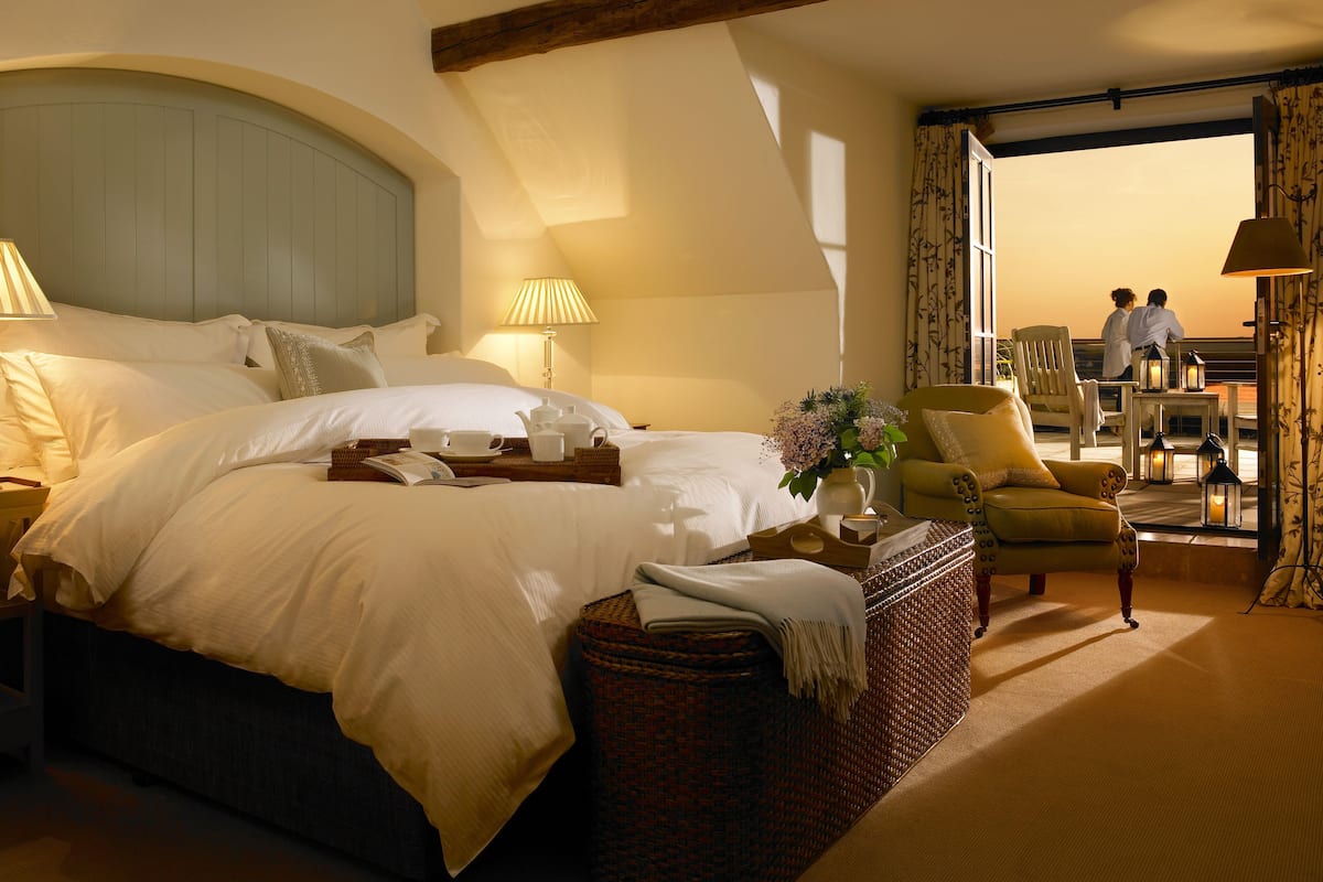 A spacious bedroom with a large bed, a chandelier, and a view of the sea.