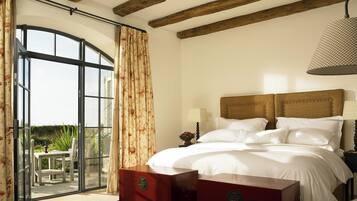 A bedroom with a bed, a nightstand, a lamp, a wooden headboard, and a view through a glass door to an outdoor area.