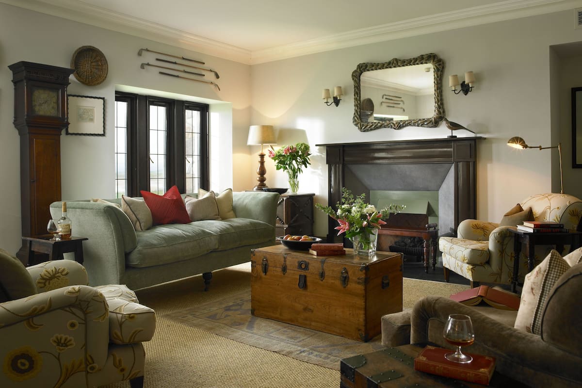 A cozy living room with a green sofa, a wooden chest, and a fireplace.