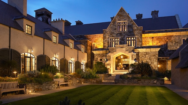A large stone building with multiple windows and a well-lit entrance. - Trump International Golf Links And Hotel Doonbeg Ireland (Doonbeg)