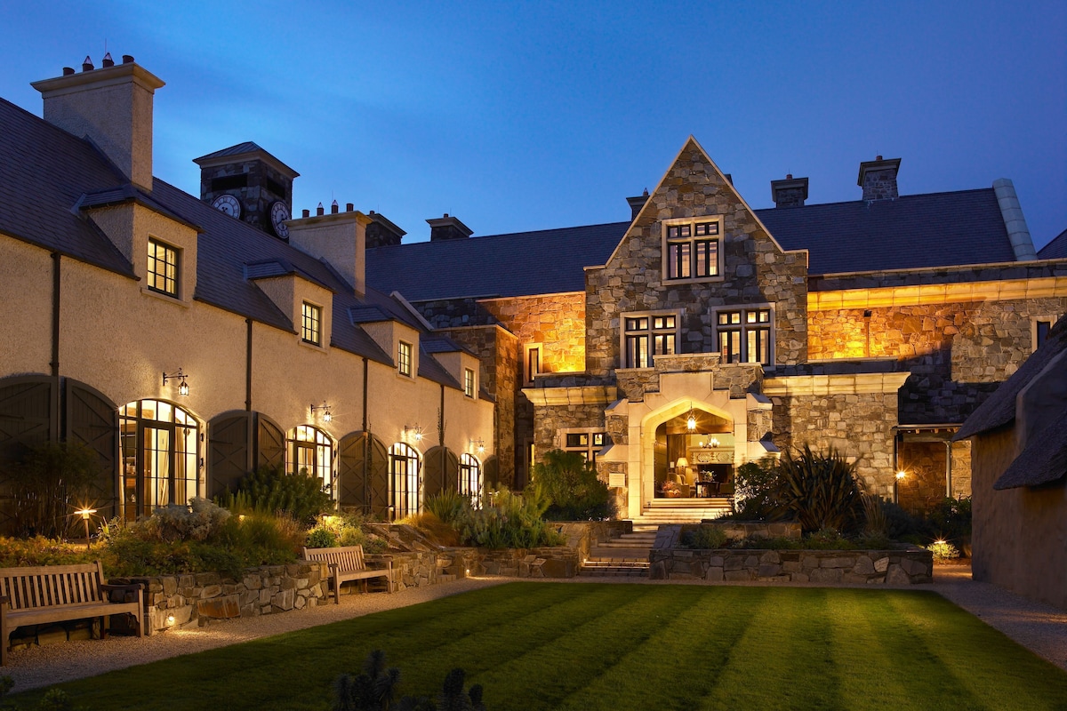 A large stone building with multiple windows and a well-lit entrance.