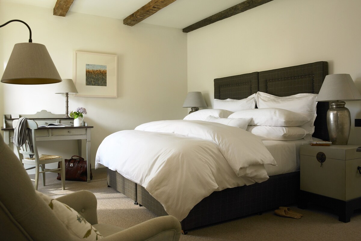 A neatly arranged bedroom with a bed, bedside tables, a desk, and a chair.