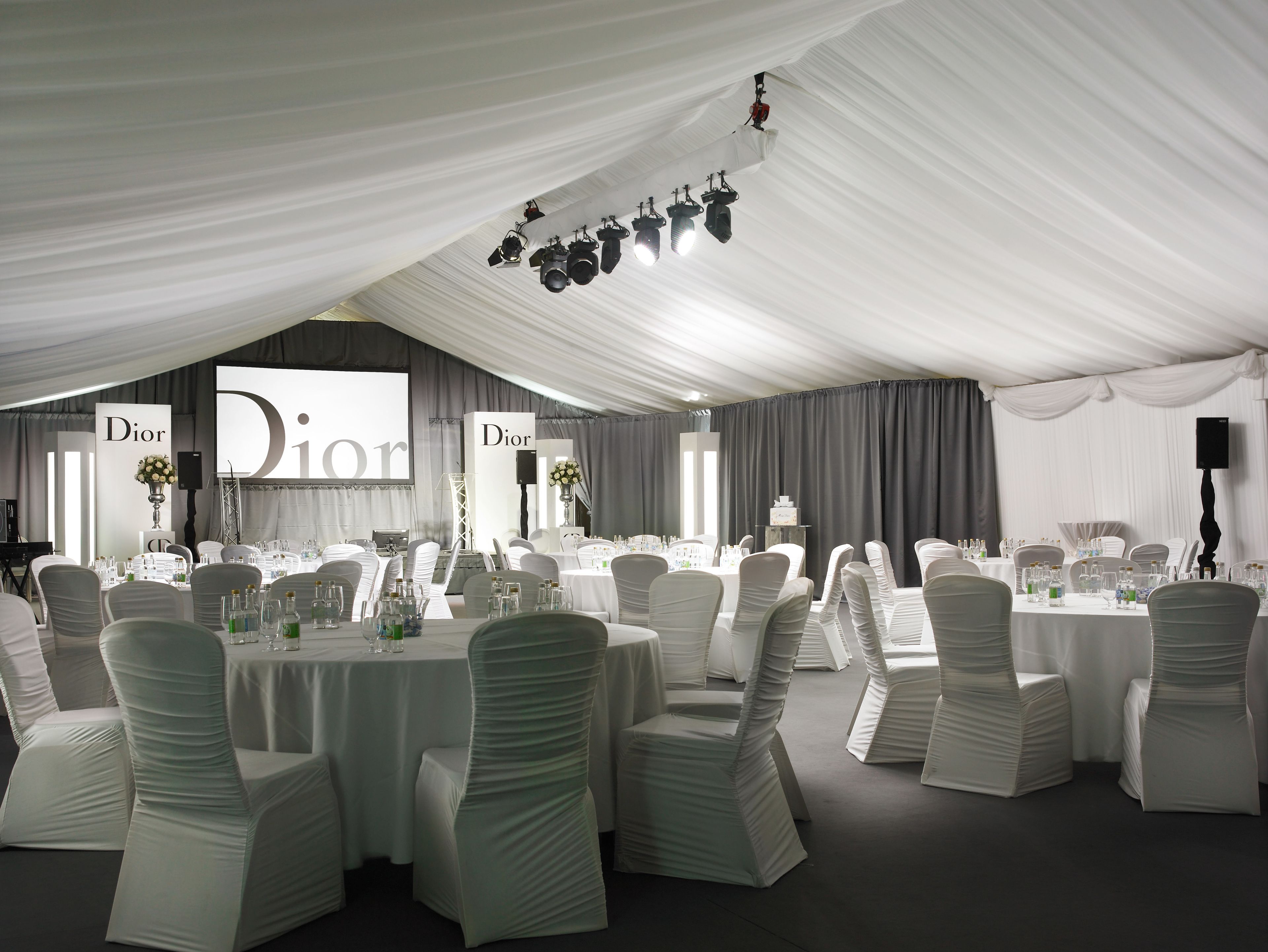 Un amplio espacio para eventos, elegantemente decorado con techos adornados con telas blancas y mesas dispuestas para una ocasión formal.